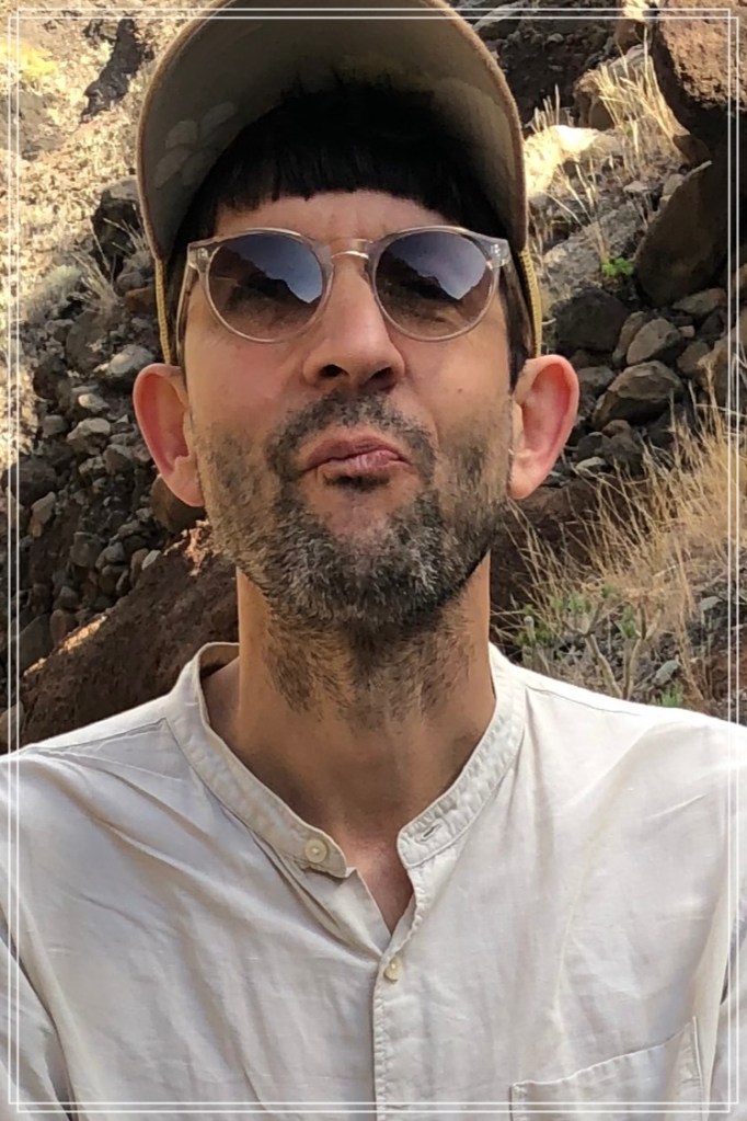 Porträtaufnahme Eric Eitel mit Cap, Sonnenbrille und weißem Hemd.