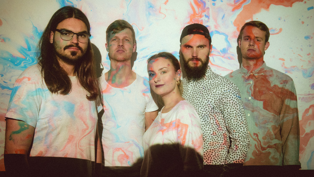 vier Männer und eine Frau farbig angestrahlt